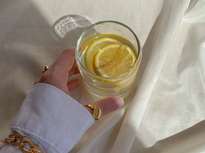 A glass of water with lemon next to a rolled-up mat.